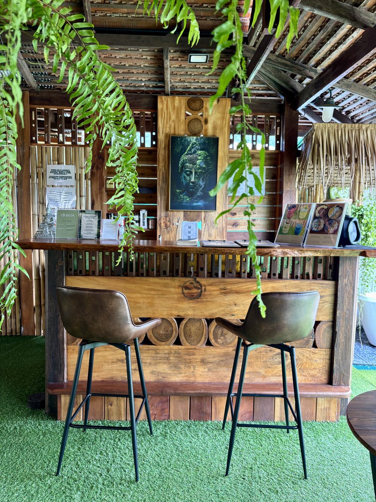 The garden café bar at Vihara under a wooden roof, ferns hanging above