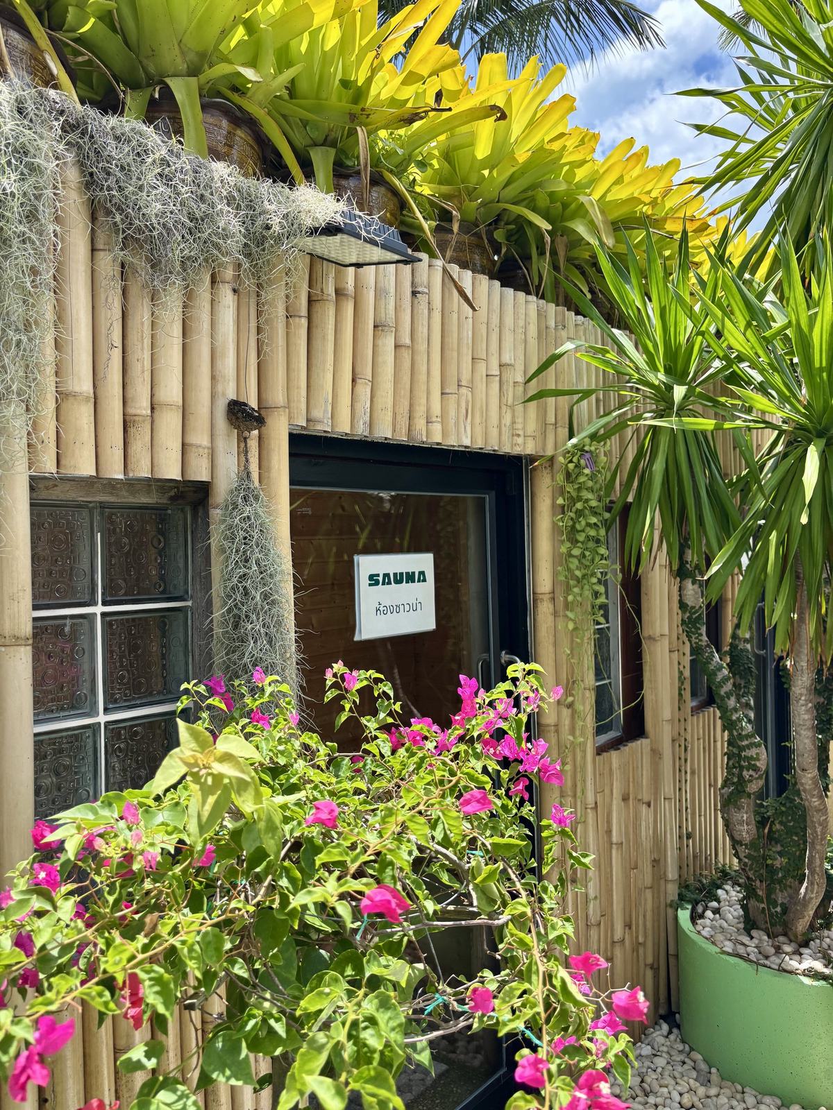 The bamboo sauna entrance at Vihara, framed by bougainvillea and bromeliads